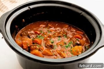 Beef Stew thickened in crockpot topped with parsley.