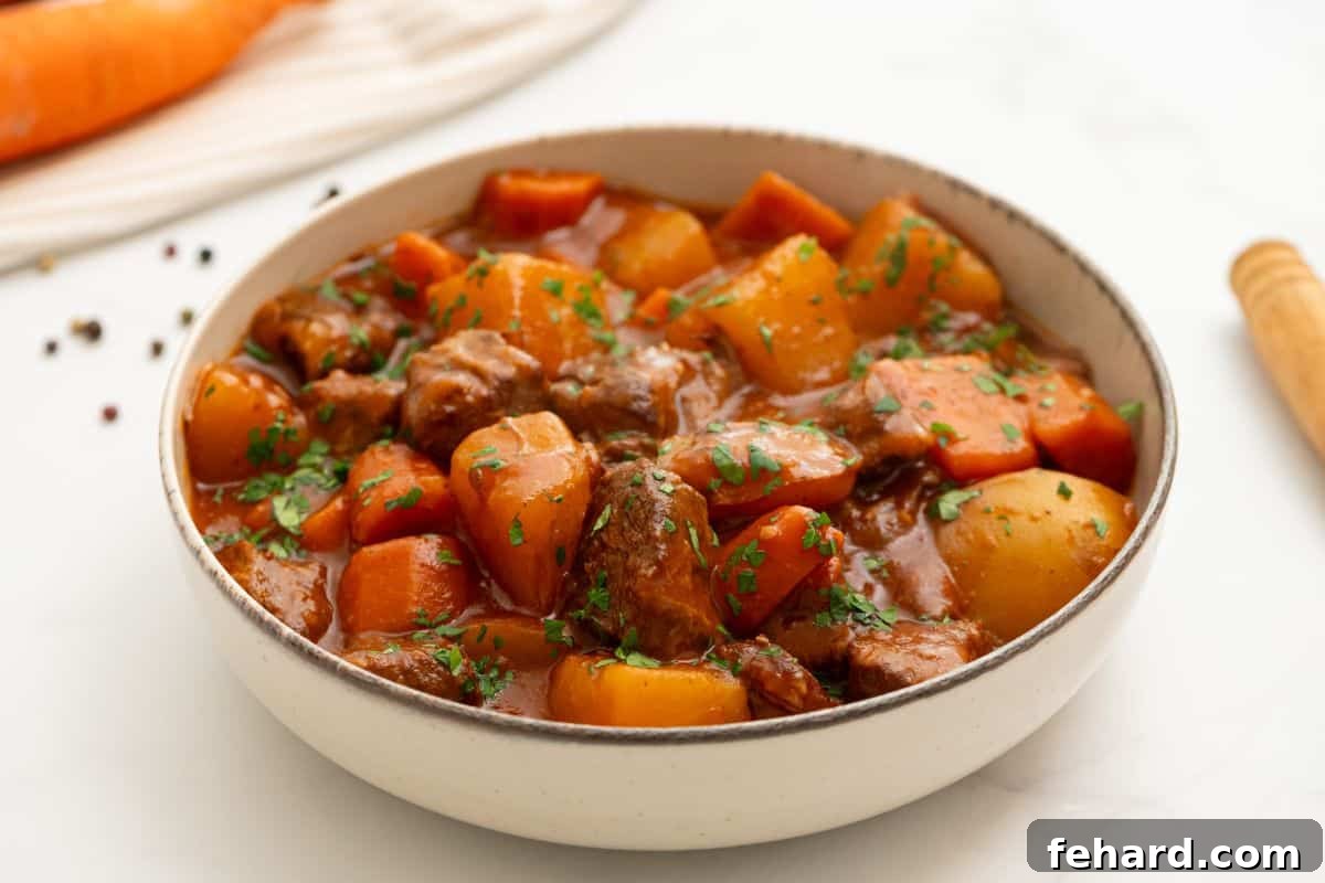 A steaming bowl of Crockpot Beef Stew, adorned with fresh parsley, showcasing tender potatoes, carrots, and a glistening thick broth.