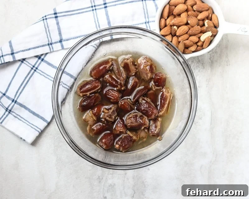 Dates soaking in hot water next to a bowl of almonds - Essential prep for homemade Larabars.