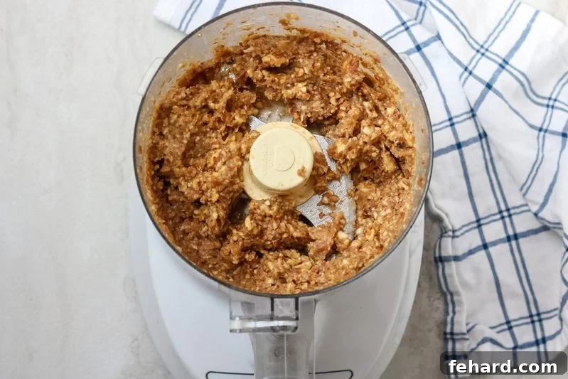 Food processor with homemade Larabar mixture, a thick paste of nuts and dates.