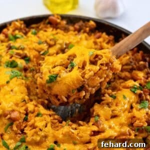 Fiesta Taco Rice Bake 2 Spoon scooping out baked taco seasoned rice with beef and beans from skillet.
