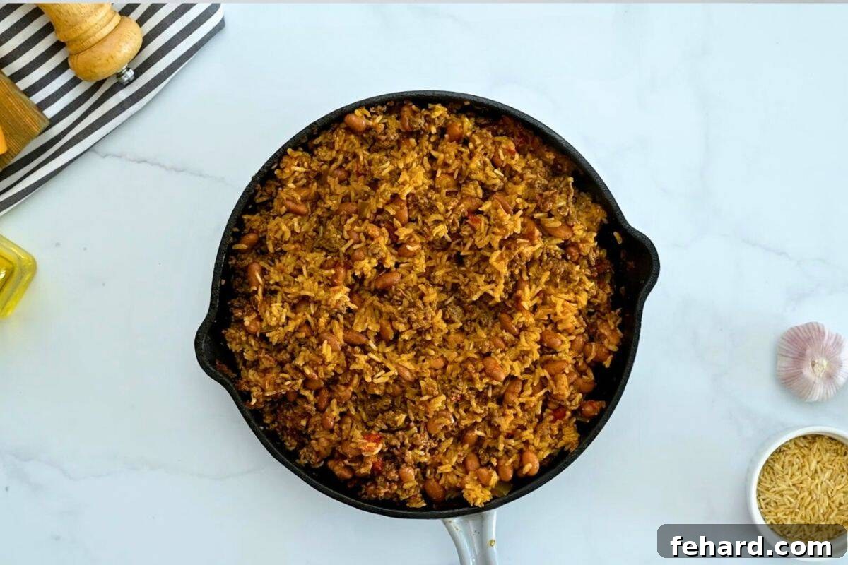 Taco and Rice Bake Baked rice with taco meat and pinto beans fluffed in a deep skillet, ready for cheese.
