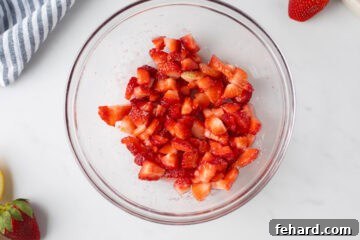 Diced strawberries in medium mixing bowl tossed with a bit of strawberries.