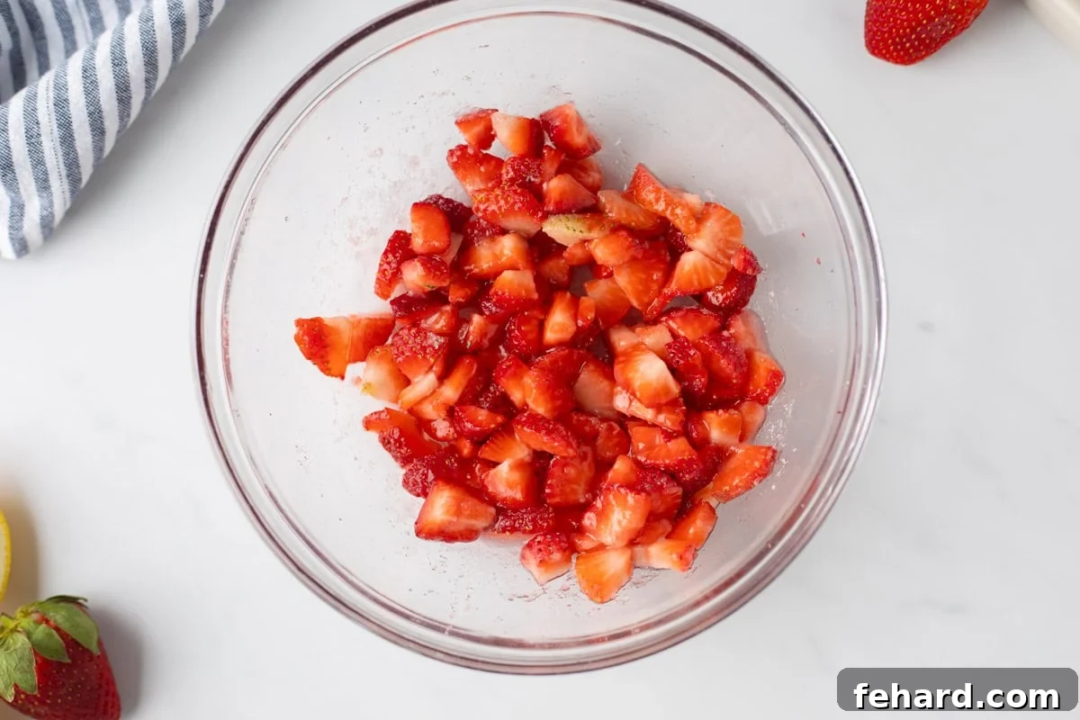 Diced strawberries in medium mixing bowl tossed with a bit of strawberries.