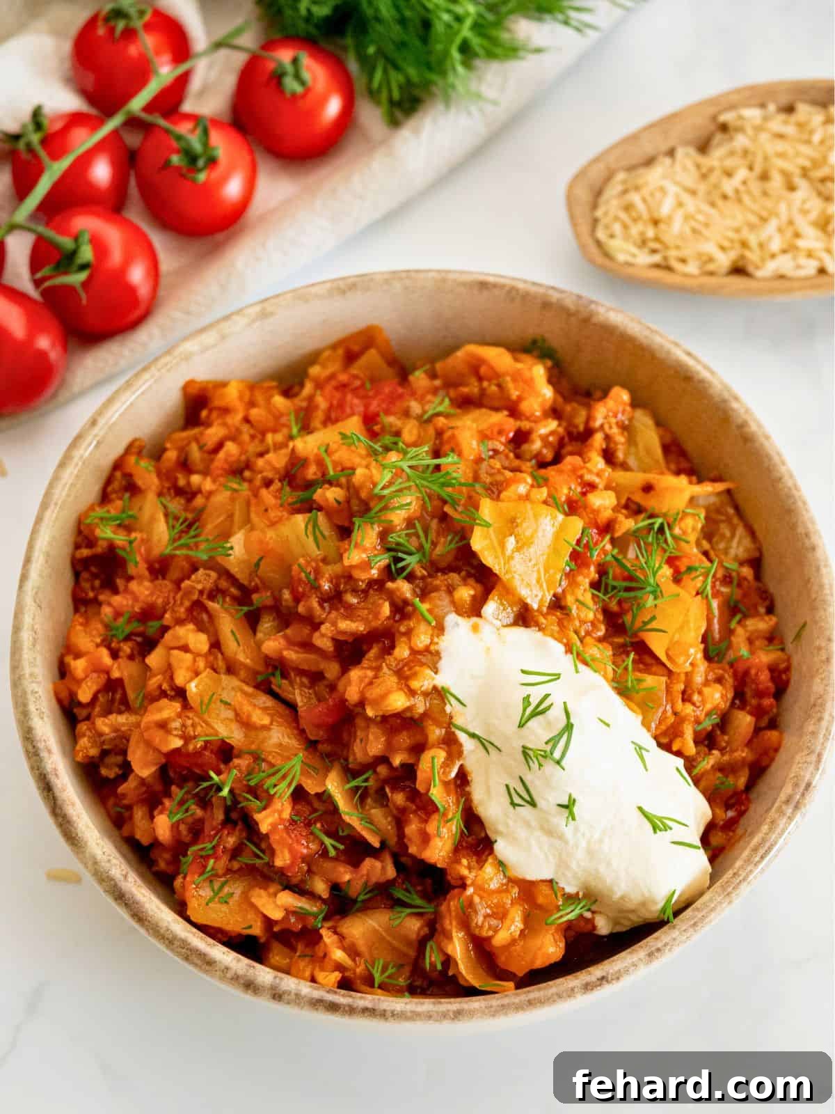 A rustic bowl of unstuffed cabbage rolls featuring diced cabbage, flavorful ground beef, and brown rice, beautifully garnished with a dollop of cool sour cream and fresh dill sprigs, ready to be enjoyed.