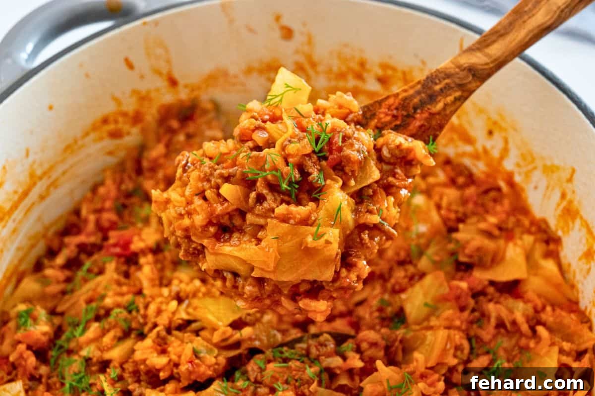 A tantalizing spoonful of perfectly cooked unstuffed cabbage rolls, gently lifted from the Dutch oven, adorned with a delicate sprinkle of fresh dill, ready to be enjoyed.