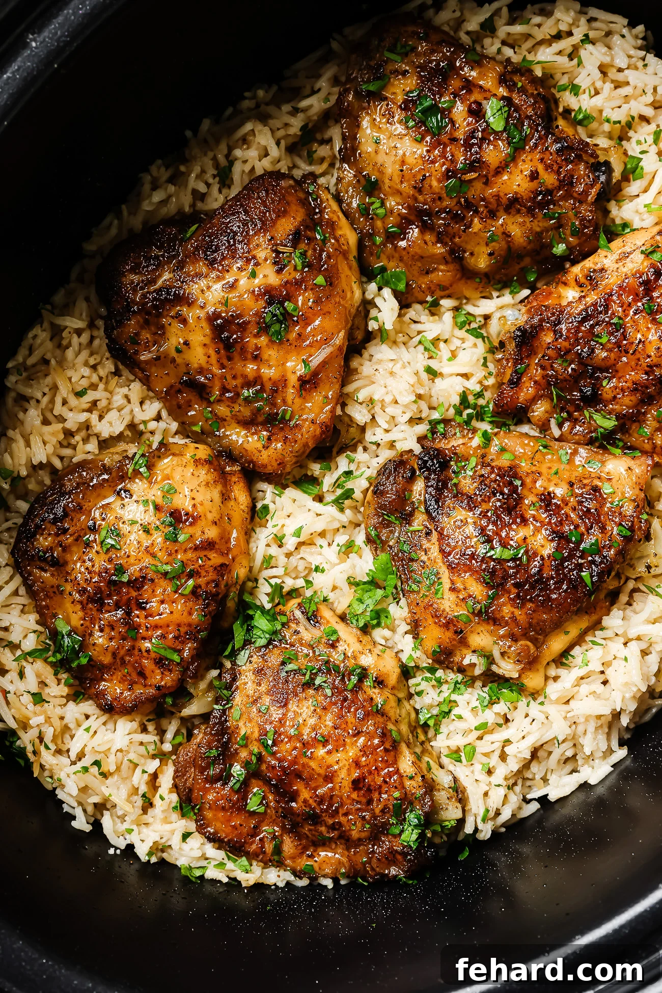 Easy Slow Cooker Chicken and Rice 2 Closeup of perfectly cooked slow cooker chicken and rice, garnished with fresh herbs, in a ceramic slow cooker bowl.