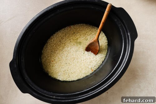 Easy Slow Cooker Chicken and Rice 12 uncooked rice and chicken broth at the bottom of a slow cooker pot.