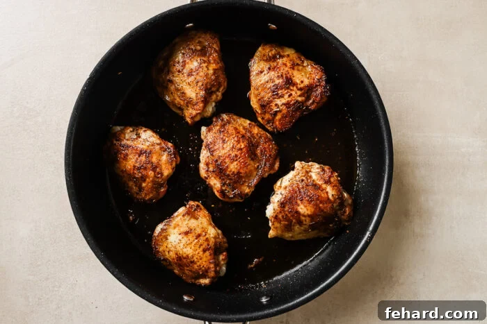 Easy Slow Cooker Chicken and Rice 3 Seasoned and seared chicken thighs in a cast iron skillet, golden brown and ready for the slow cooker.