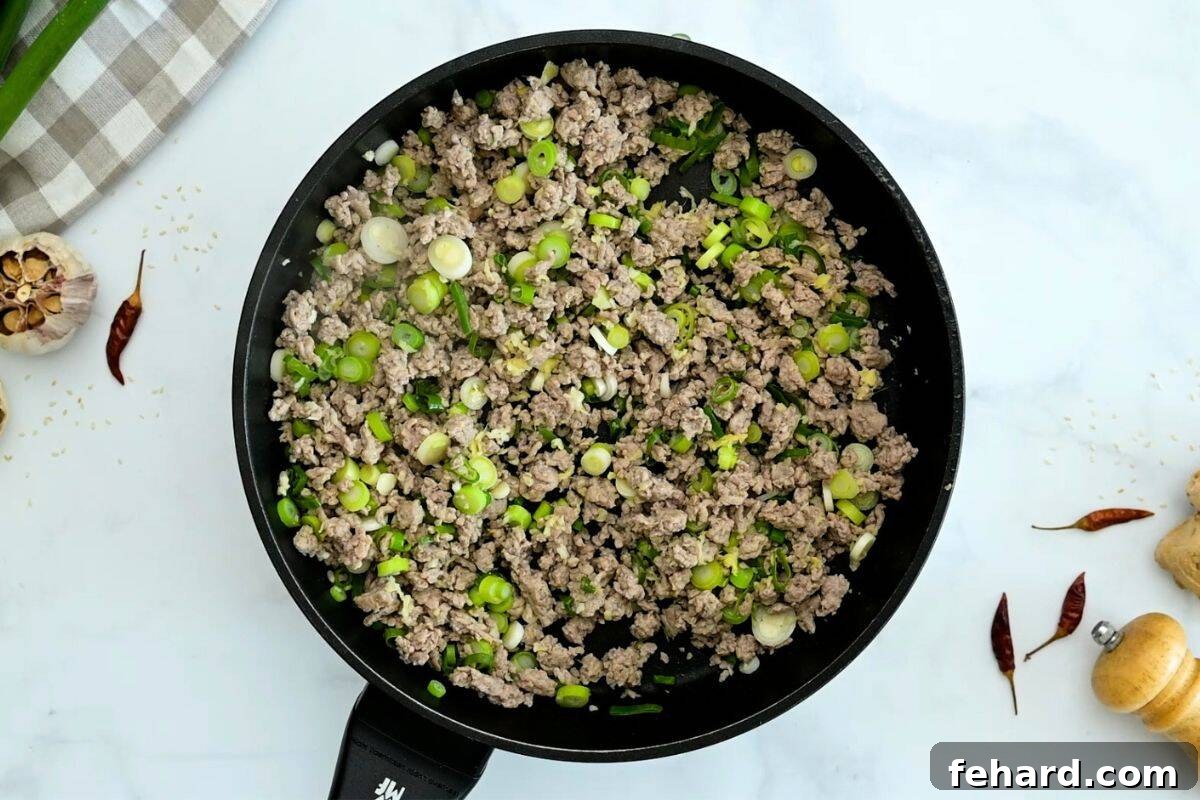 Egg Roll Bowl Recipe Browned ground turkey with green onions in skillet for base of egg roll in bowl.