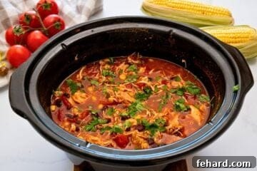 Slow cooker filled with chicken tortilla soup made with beans, corn, shredded chicken and a rich spiced tomato base.