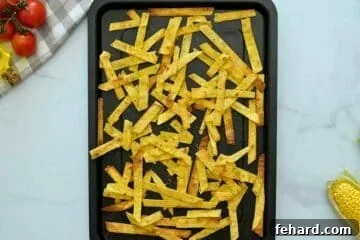 Baked crispy corn tortilla stirps on baking sheet after being coated in oil, seasonings, and baked until crispy.