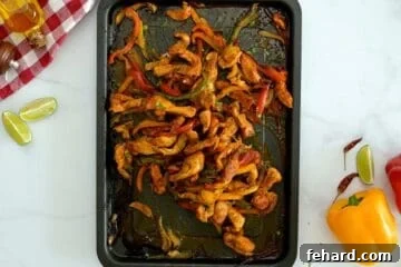 Chicken and peppers with onions roasted on sheet pan topped after finishing with lime zest and lime juice.
