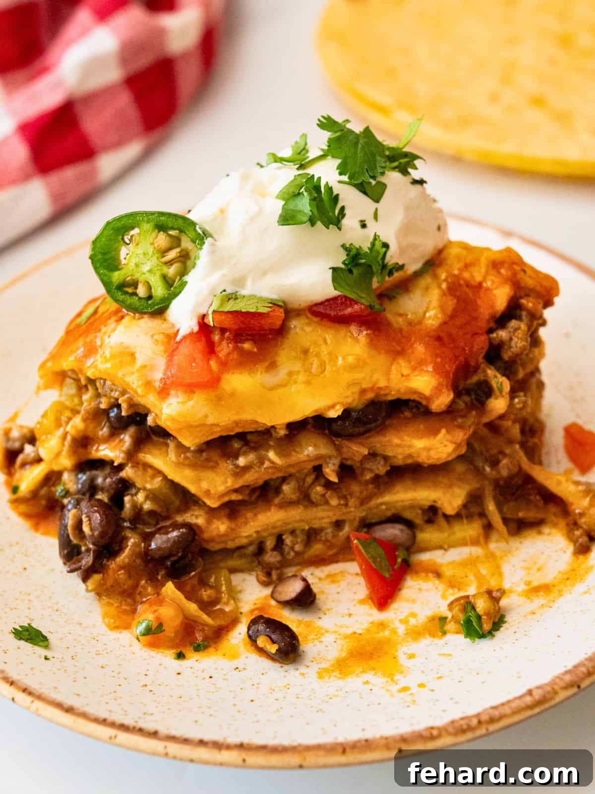 A close-up shot of a slice of beef enchilada casserole on a plate, showcasing the distinct, delicious layers.