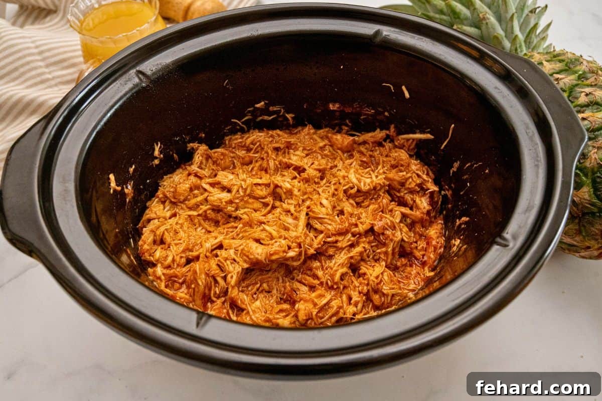 Crockpot Pulled Chicken Shredded BBQ Chicken in slow cooker after being tossed with BBQ sauce.