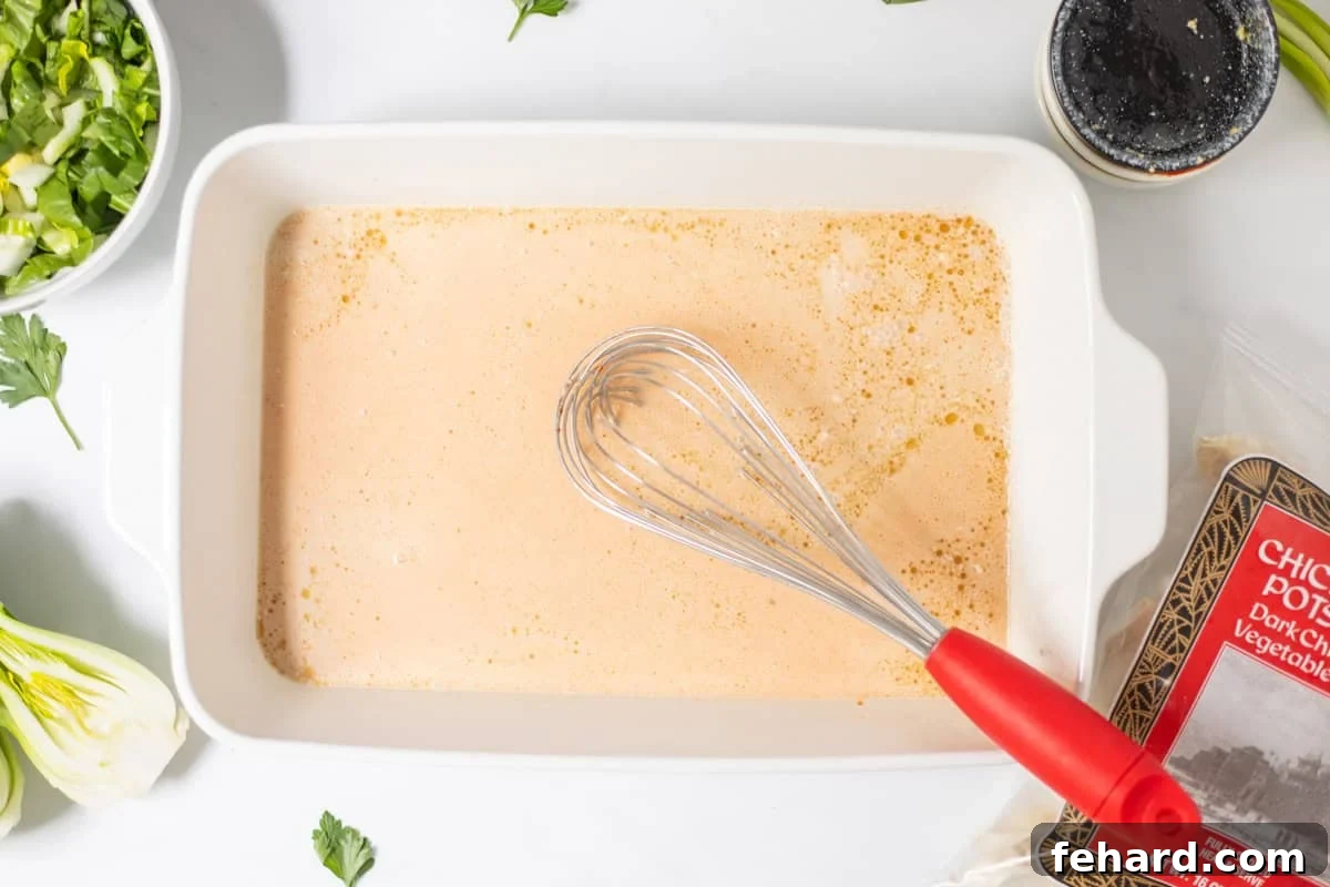 Canned coconut milk, soy sauce, sesame oil, curry paste, and rice vinegar in 9x13 inch baking dish with red whisk next to bag of frozen chicken and pork potstickers.