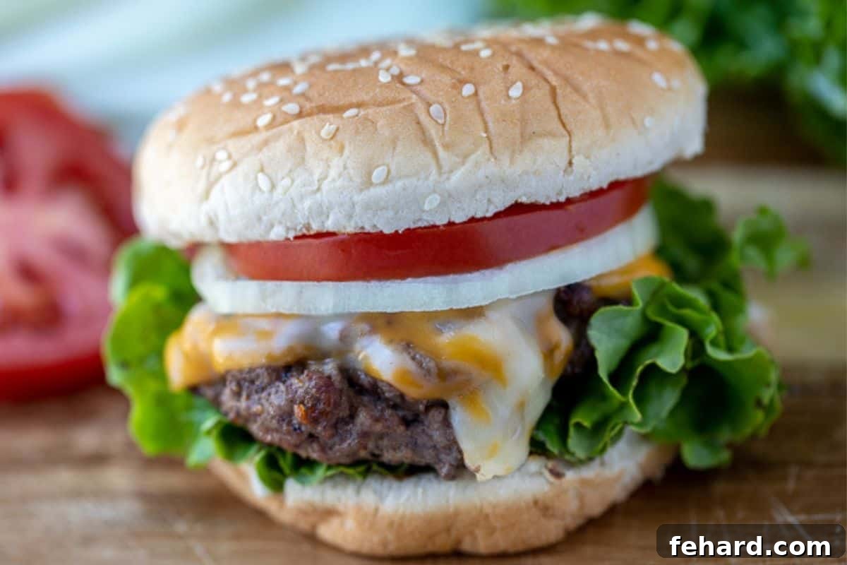 Homemade Burger on cutting board on bun topped with with lettuce and tomatoes.