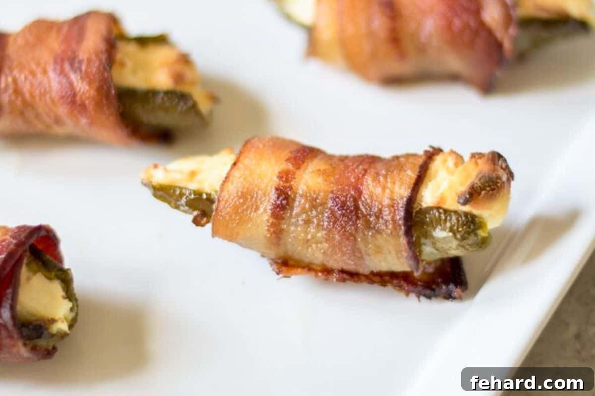 Bacon-wrapped jalapeno poppers on white plate.