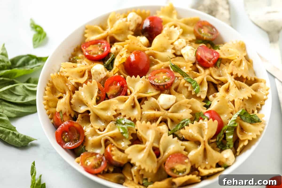 Bowl of Caprese Pasta Salad next to fresh basil.