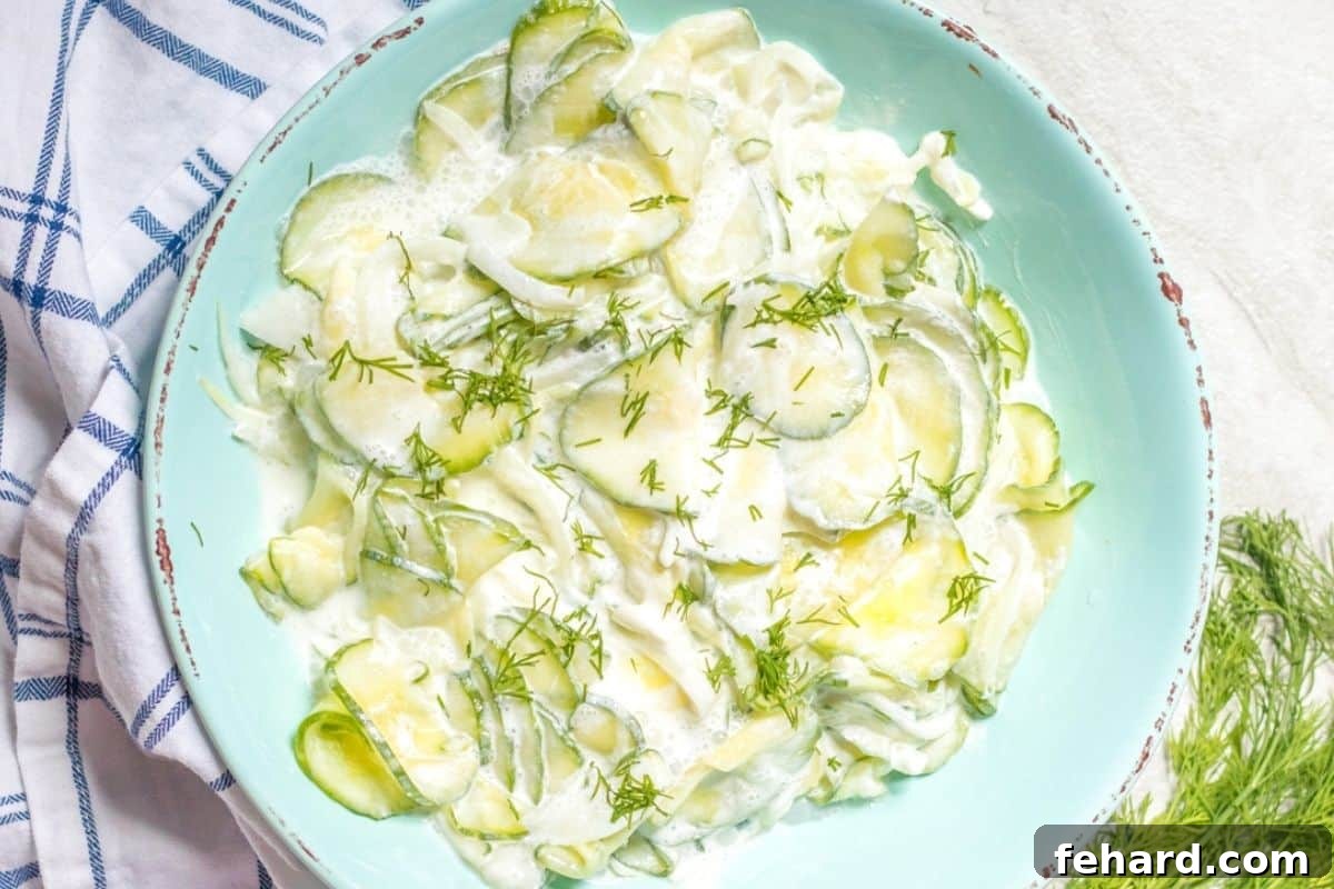 Creamy cucumber salad with dill in blue mixing bowl.