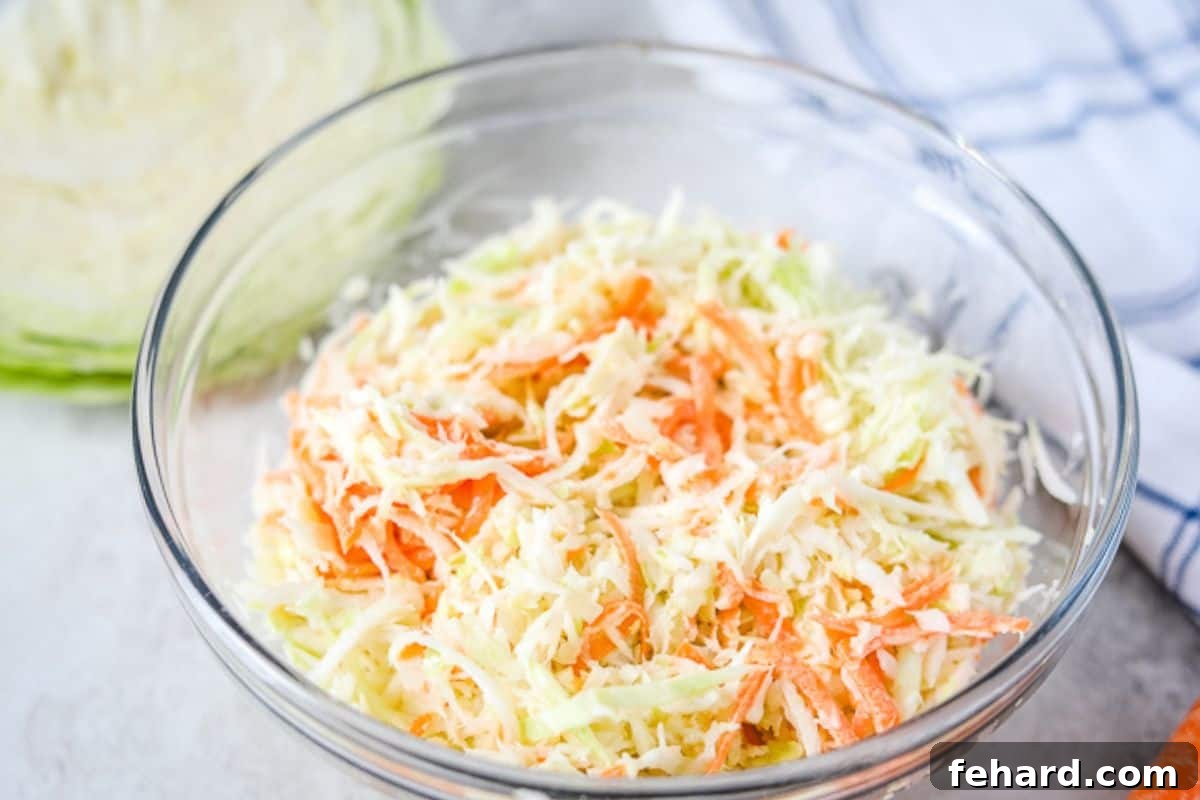 Bowl of homemade creamy coleslaw made with green cabbage and shredded carrots.