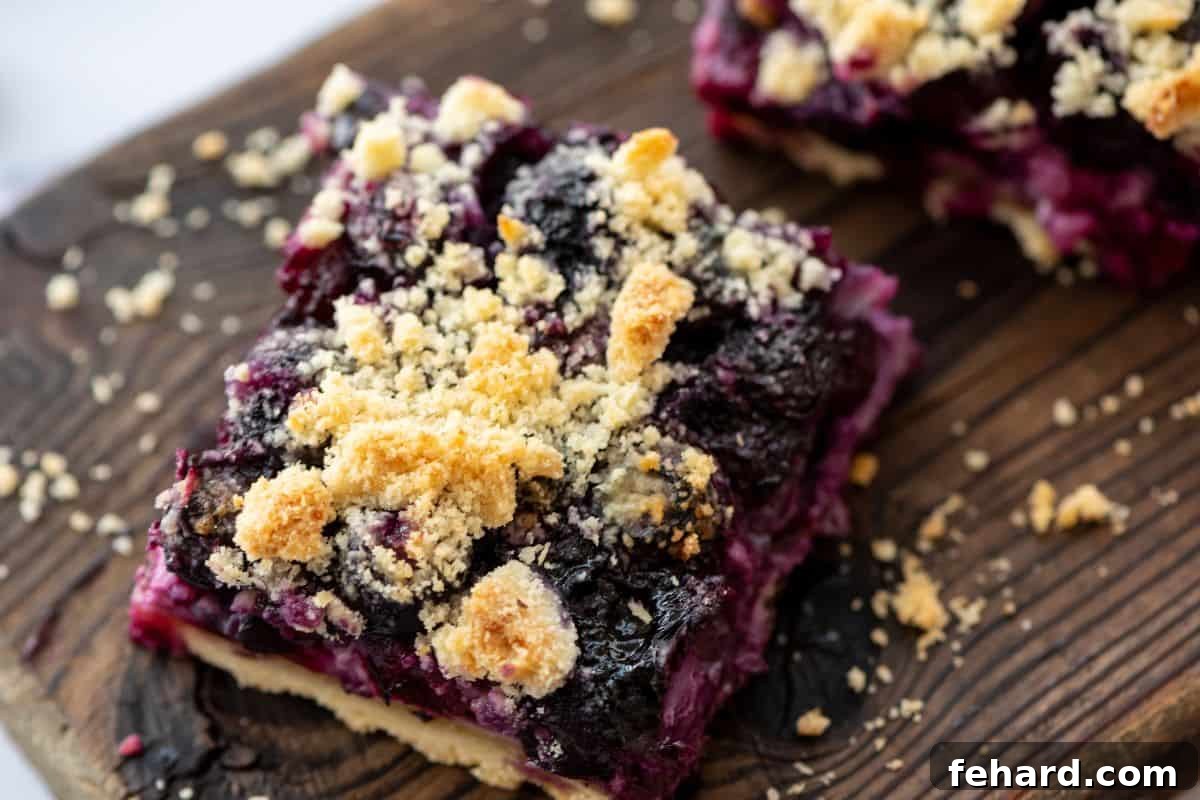 Sliced blueberry pie bars on wooden cutting board showing shortbread crumble.