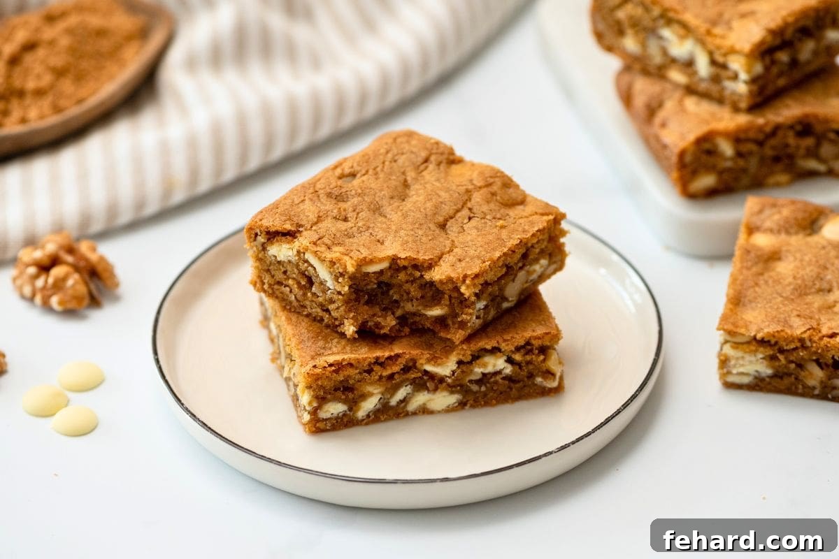 Two Browned Butter Blondies with white chocolate chips and walnuts cut into squares on plate.