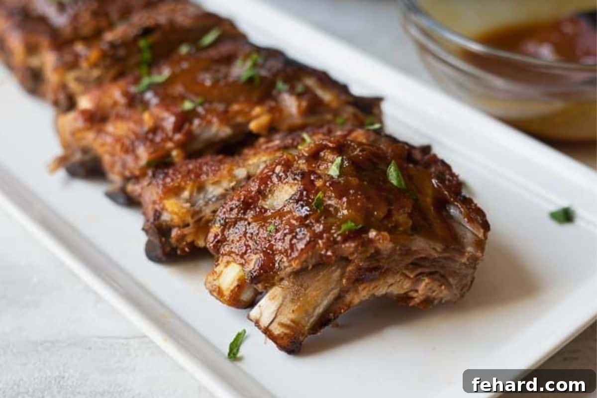Pork Baby Back ribs that have been cooked in Instant Pot on white platter finished with BBQ sauce.
