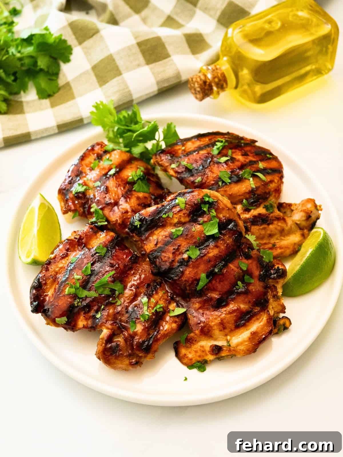 Grilled thighs that were marinated in cilantro lime marinade on platter topped with fresh cilantro next to fresh lime wedges.