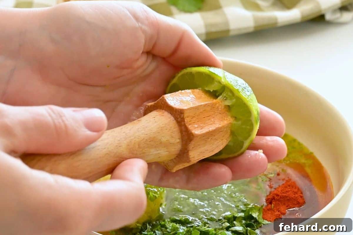 Lime being juiced over small bowl for cilantro lime marinade for chicken.