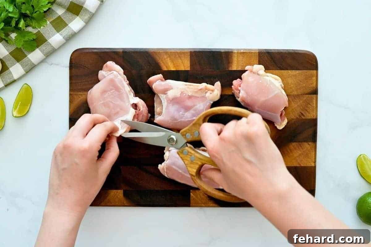 Kitchen shears trimming fat and grizzle from chicken thighs before marinating with cilantro lime marinade.