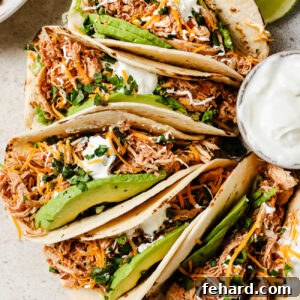 Slow Cooker Shredded Chicken Tacos with Flavorful Salsa 11 Slow Cooker Chicken Tacos with fresh toppings on a kitchen countertop.