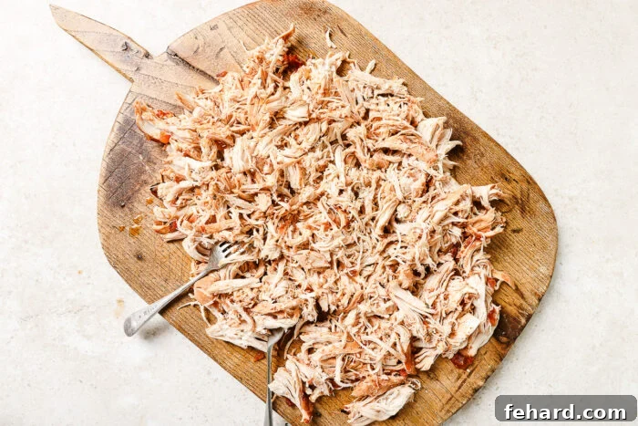 Slow Cooker Shredded Chicken Tacos with Flavorful Salsa 7 Tender shredded chicken on a wooden cutting board.