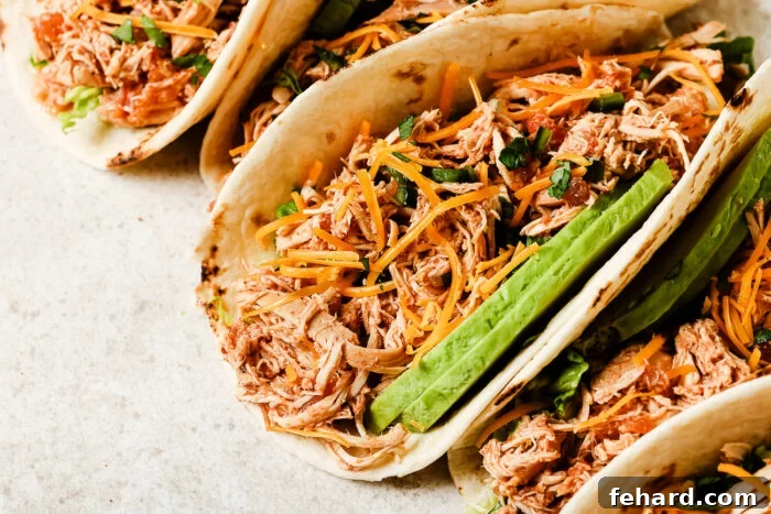 Slow Cooker Shredded Chicken Tacos with Flavorful Salsa 9 Close-up view of slow cooker chicken tacos filled with shredded chicken, salsa, and fresh toppings.