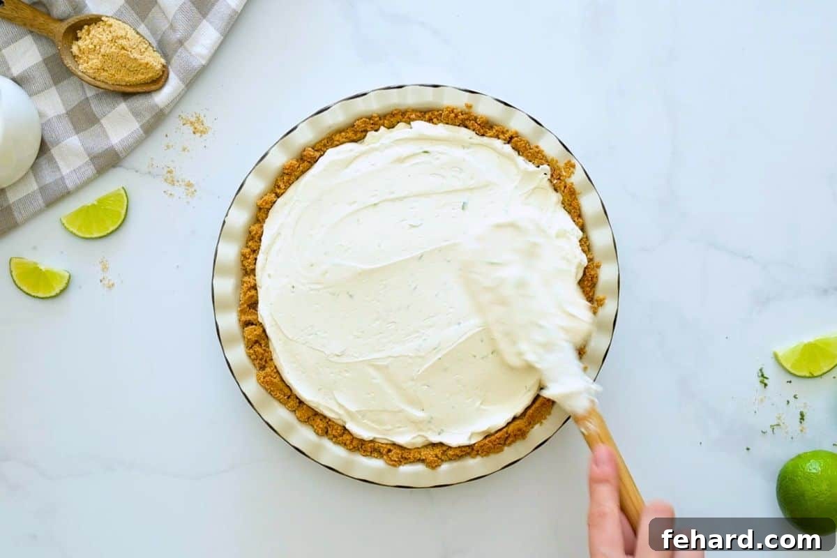 Key Lime Pie Recipe without Cool Whip Spatula spreading the no bake key lime pie filling into homemade graham cracker crust.