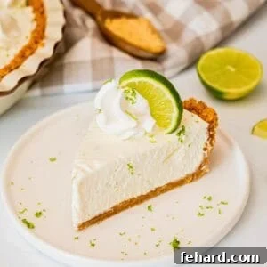Simple Homemade Key Lime Pie Recipe 3 Slice of no bake key lime pie with graham cracker crust on plate topped with piped whipped cream, a lime slice, and lime zest.