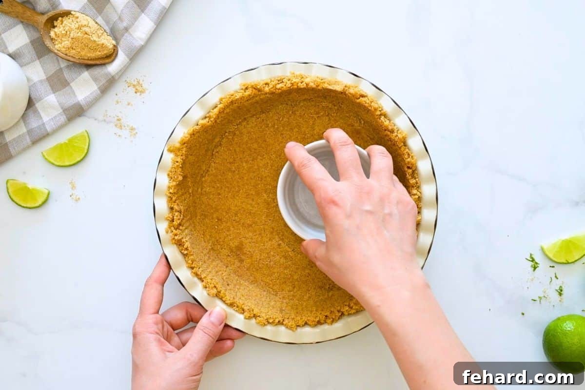 Easy Key Lime Pie with Homemade Graham Cracker Crust Cup pressing graham cracker crust into homemade pie plate.