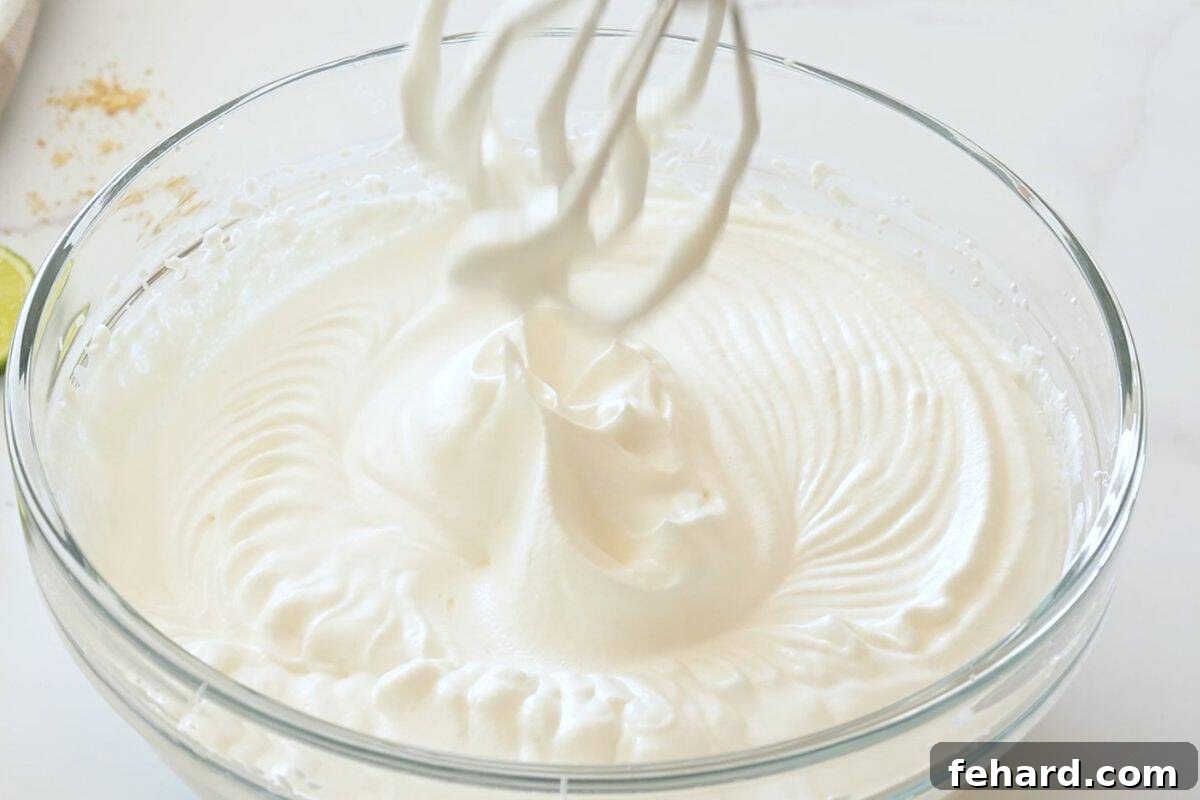 key lime pie recipe with sweetened condensed milk Mixing bowl with beaters showing softly whipped heavy cream holding gentle peaks.
