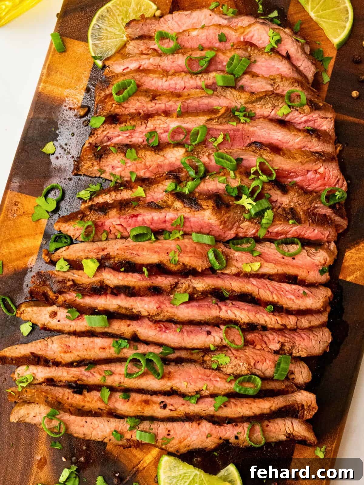 Marinated grilled flank steak sliced against the grain topped with cilantro, green onions, lime slices.