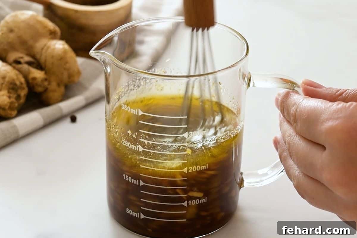 Soy sauce, brown sugar, lime juice, garlic, ginger, being mixed together in glass measuring cup.