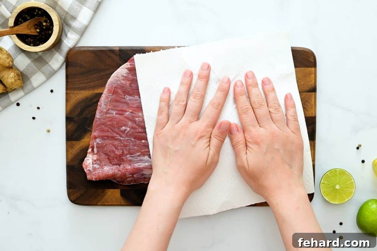 Paper towel blotting flank steak to remove excess moisture.