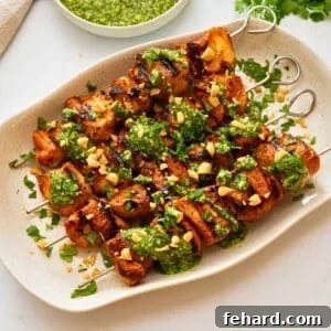 Grilled Chicken Kabobs with Zesty Cilantro Pesto 3 Grilled chicken kabobs on white platter topped with cilantro pesto, fresh cilantro, and chopped peanuts.