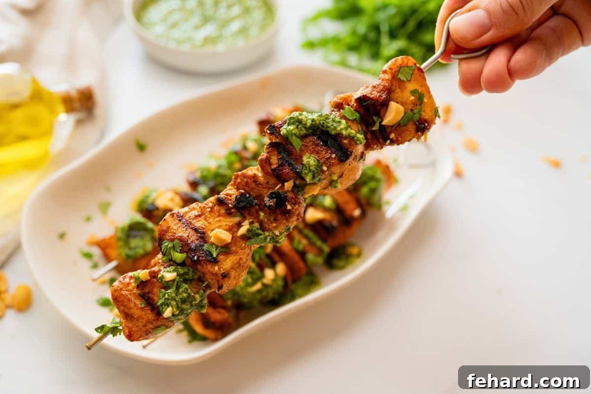 Chicken Kabobs on Grill Close up of one grilled chicken kabobs topped with cilantro pesto, fresh cilantro, and chopped peanuts.