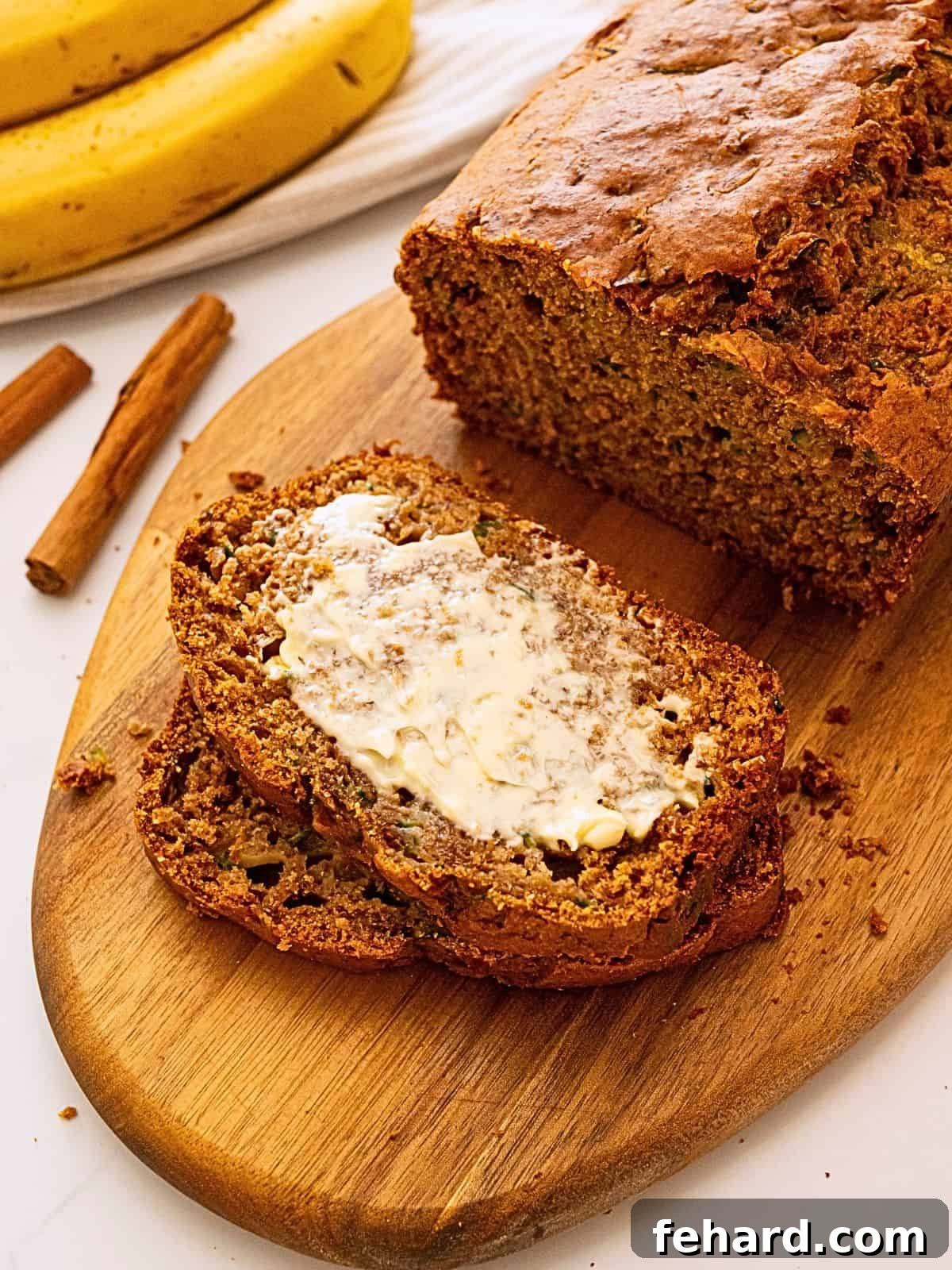 Zucchini Banana Bread A slice of Zucchini banana bread on cutting board with generous smear of softened butter.