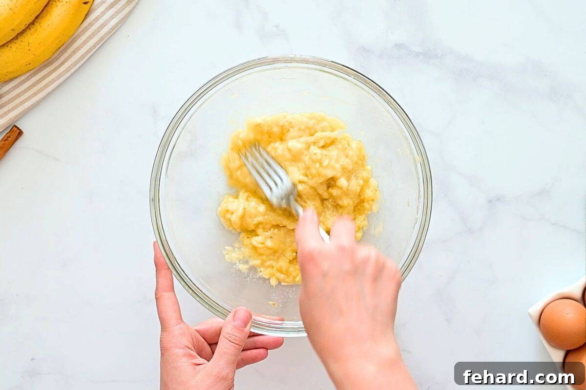 Zucchini Bread with Banana Fork mashing ripe banana in large mixing bowl.