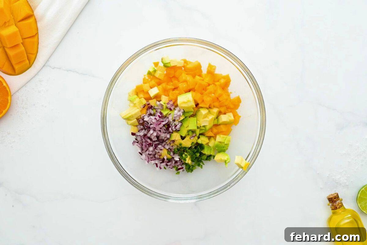 Diced mango, diced avocado, minced red onion, minced jalapeno, lime juice, salt, and cilantro combined in mixing bowl.