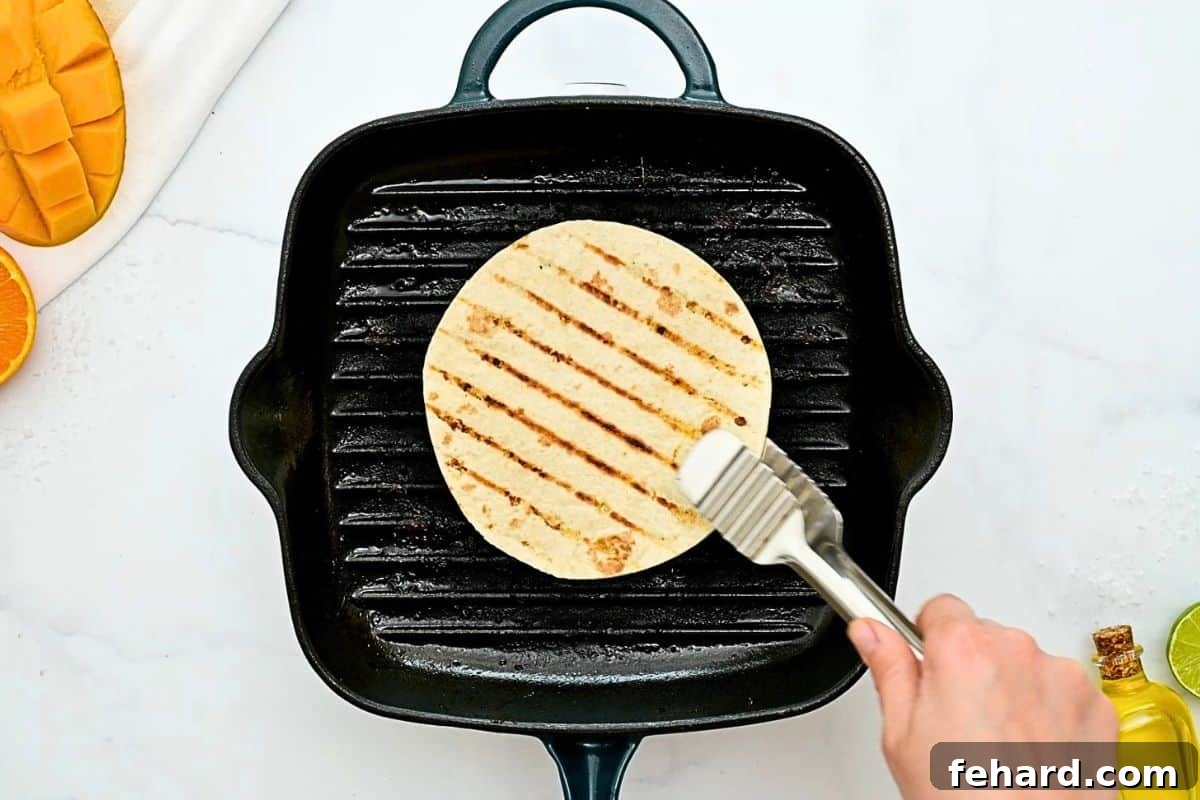 Flour tortilla being removed from grill plate after lightly toasting on each side.