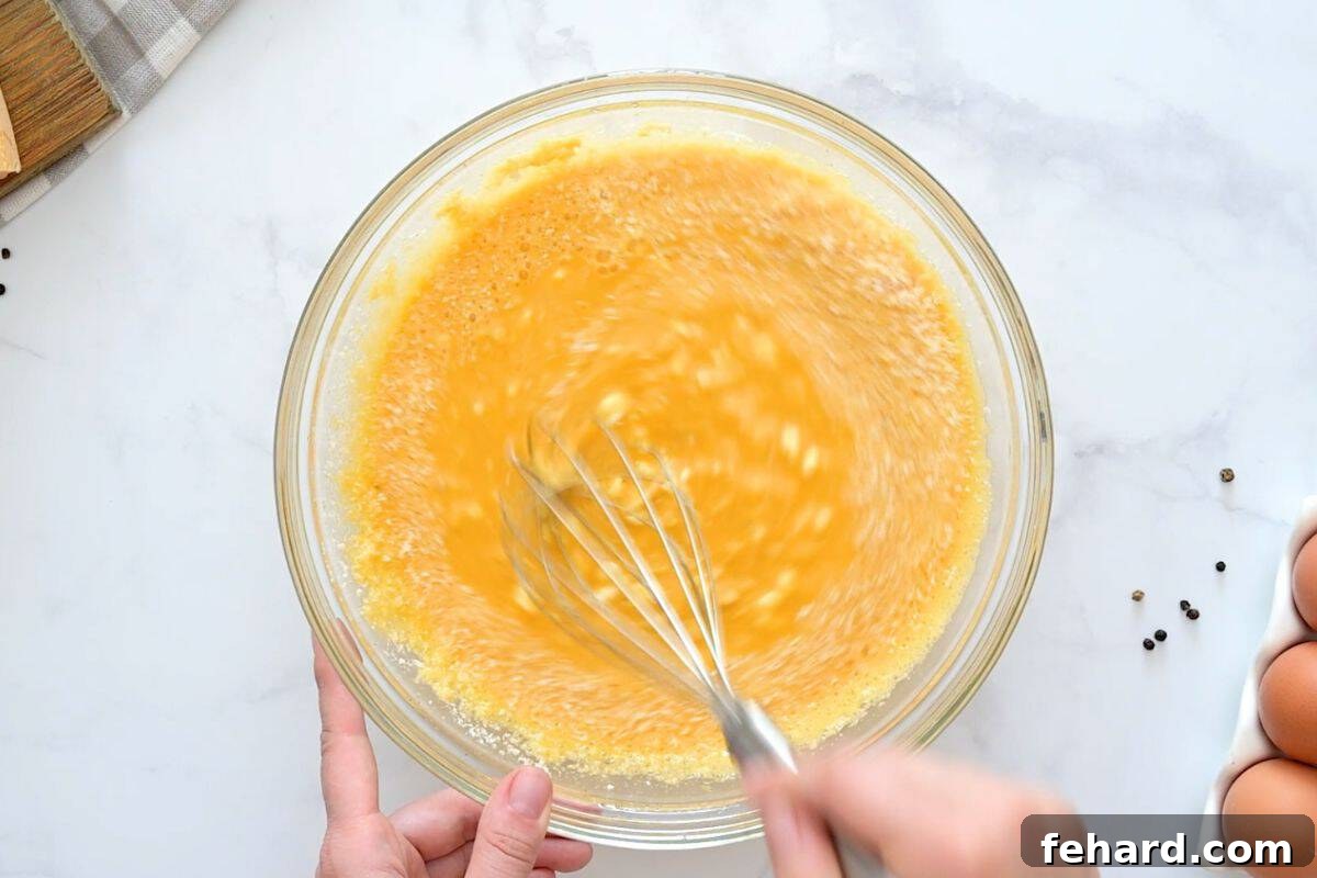 Cottage Cheese and Egg Bake Whisk mixing cottage cheese, parmesan, and shredded cheese into eggs in large mixing bowl.