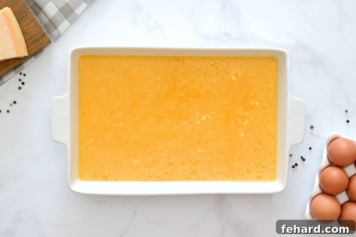 Egg Bake with Cottage Cheese Eggs mixed with cottage cheese, shredded cheese, and parmesan poured into a white 9x13 inch baking dish.
