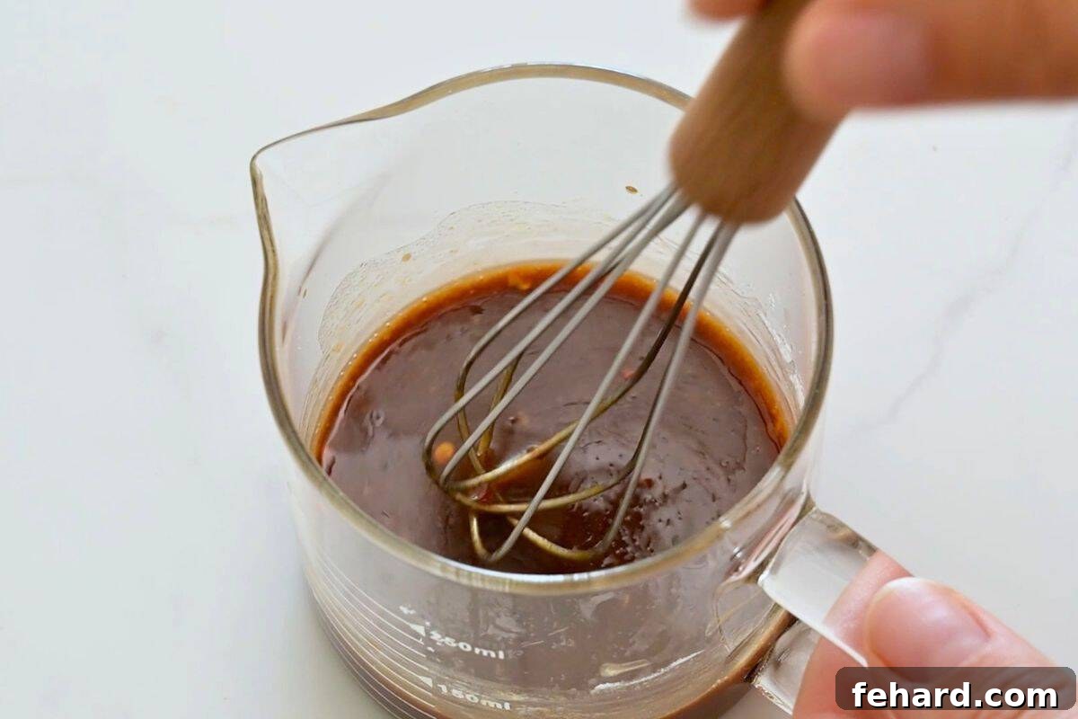Easy Ground Beef Korean Rice Bowl Recipe Gojuchang, soy sauce, honey, rice wine vinegar, and cornstarch being whisked together in small glass jar.